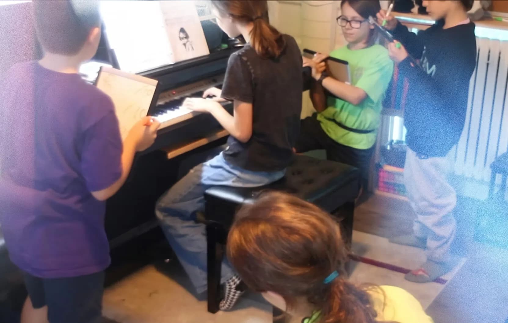 A group of students gathered around the piano during a class.